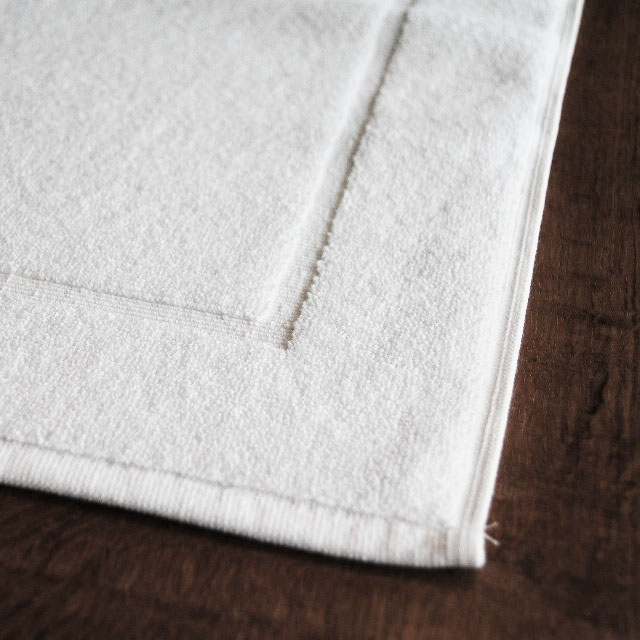 Close-up van een luxe witte badmat van Blycolin
