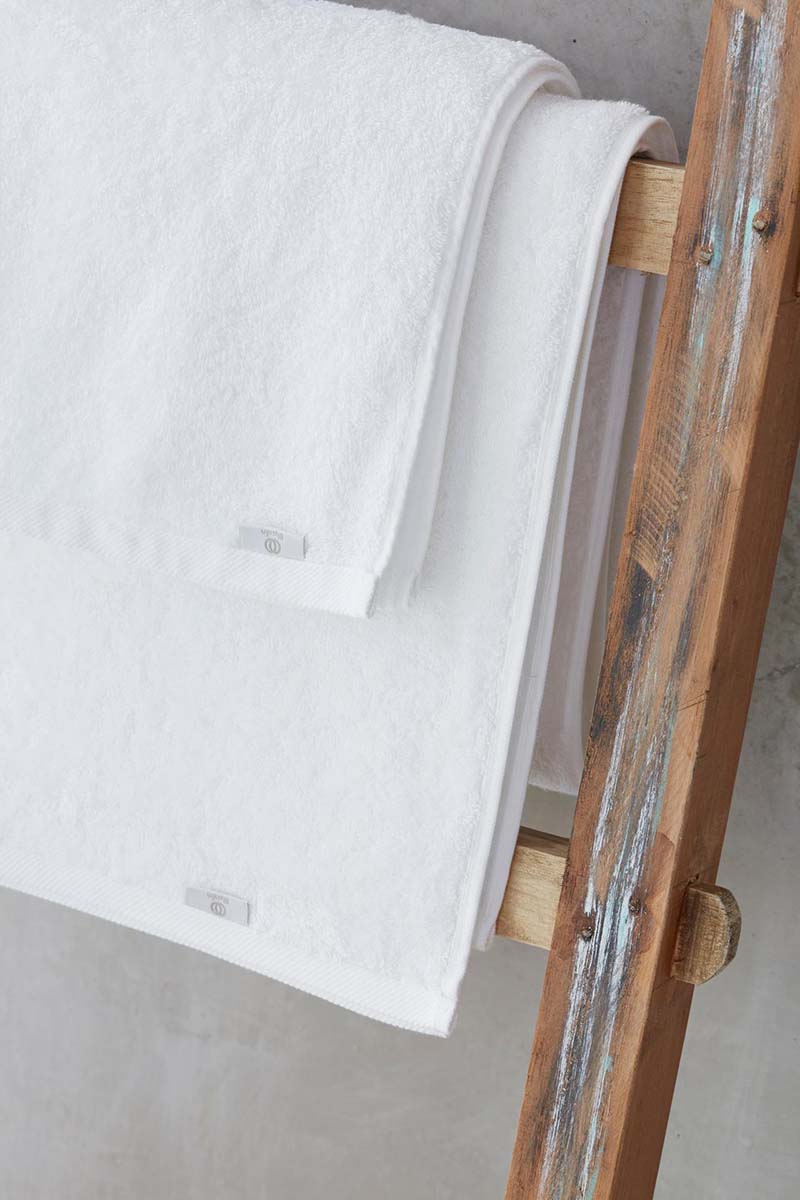 Witte handdoeken uit de Mare-lijn van Blycolin over een houten ladder