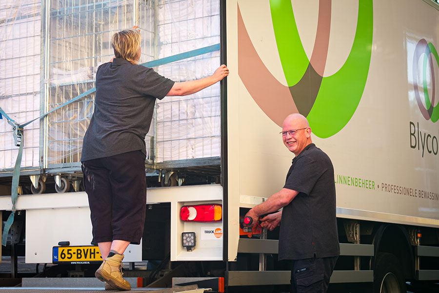 Twee medewerkers van Blycolin laden linnenkarren in een vrachtwagen