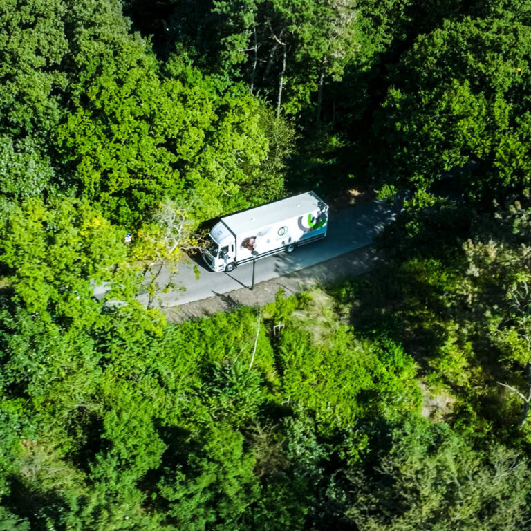 Luchtfoto van een vrachtwagen van Blycolin op een weg door het bos