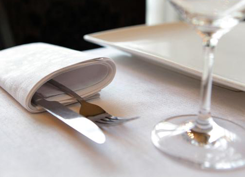 Servet met bestek op een gedekte tafel met wijnglas
