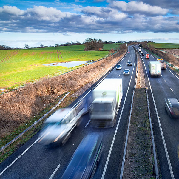Snelweg met vrachtwagens tussen groene weilanden